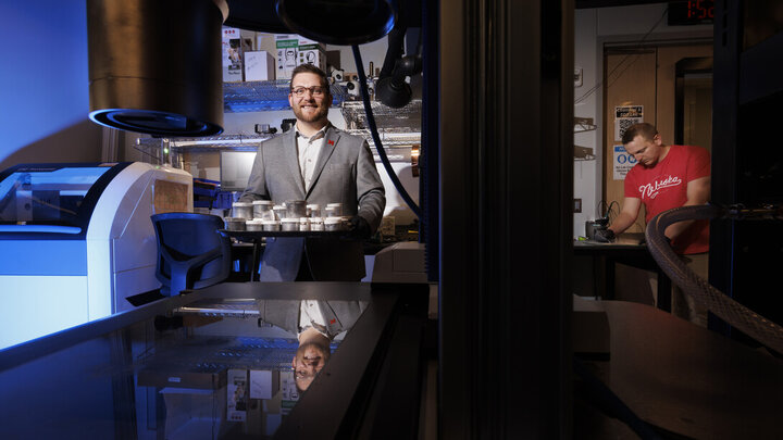 Eric Markvicka (left), assistant professor of mechanical and materials engineering, holds a tray of liquid metal samples while graduate student Ethan Krings works on a sample at right.