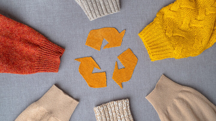 A recycling sign made with fabric surrounded by sweater sleeves.