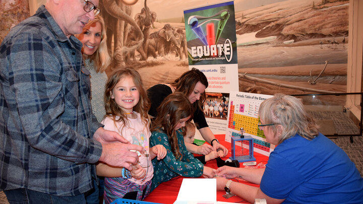 A young girl smiles at the camera while learning about circuits at Sunday with a Scientist.